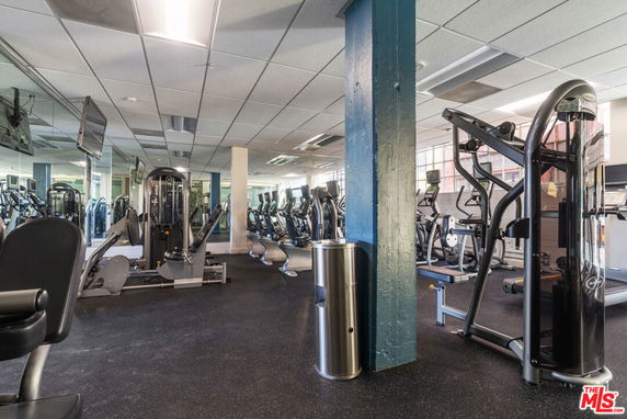 Indoor gym area with various exercise equipment and mirrored walls.