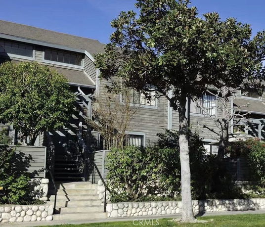 Front view of a multi-story house with wooden siding and stairs leading to the entrance.