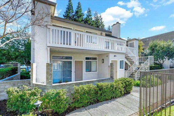 Front view of a two-story house with exterior stairs and a balcony.
