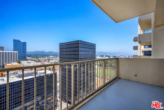 Balcony view overlooking city skyline and distant hills.