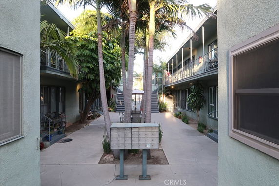 View of a two-story apartment building with a central courtyard and palm trees.