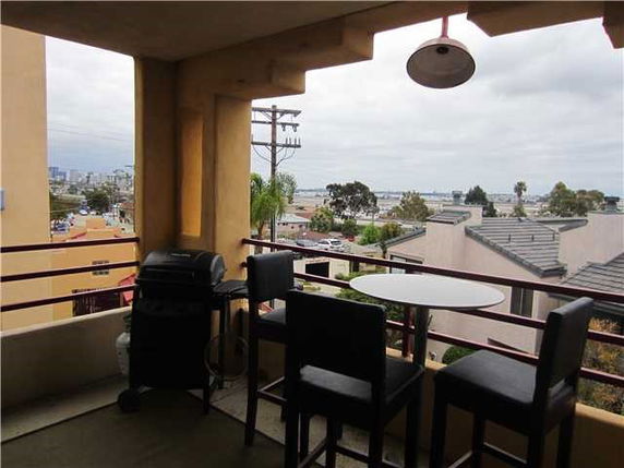 Balcony view with outdoor furniture overlooking rooftops and a distant cityscape.