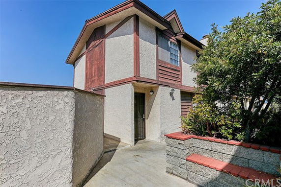Front view of a multi-story house with a unique roof design and surrounding walls.