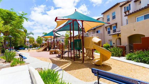 Outdoor playground with slides and climbing structures near residential buildings.