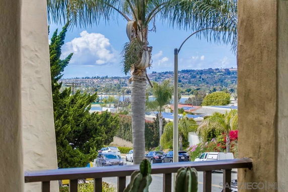 Panoramic view from a building, showing a suburban area with palm trees and distant hills.