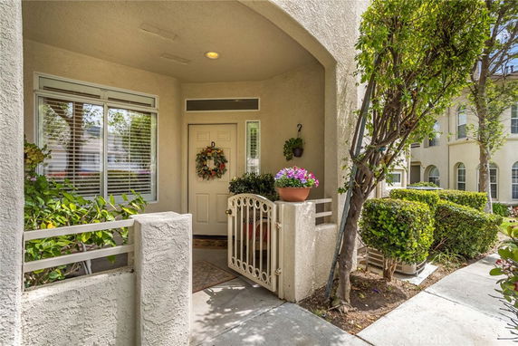Front view of a house entrance with a small porch area, decorative wreath on the door, and potted plants.