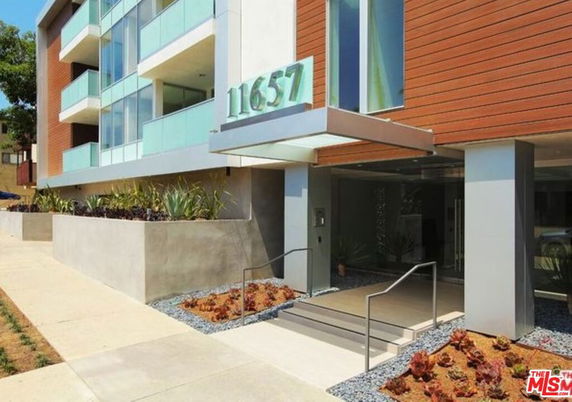 Front view of a modern multi-story building with glass balconies.