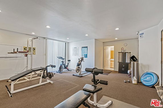 Room with gym equipment including benches, exercise bikes, and weights.