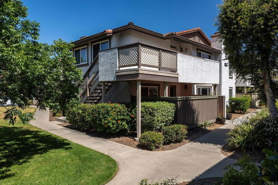 Front view of a two-story residential building with a balcony and exterior staircase.