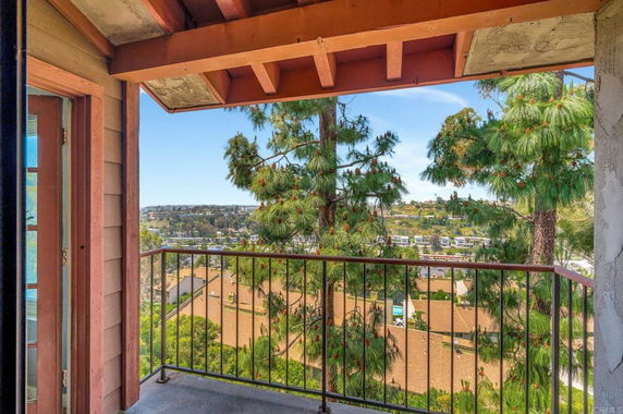 View from a balcony showing the surrounding landscape with trees and buildings.