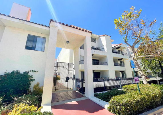 Front view of a multi-story building with balconies and a gated entrance.
