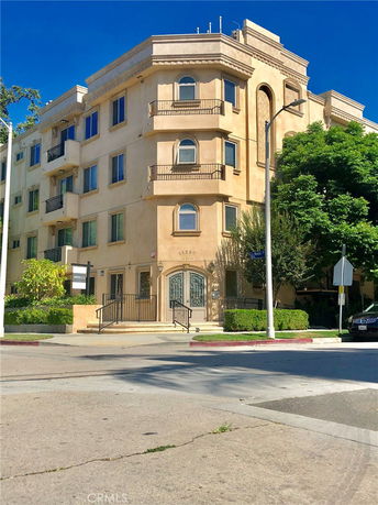 Front view of a multi-story apartment building with balconies and a gated entrance.