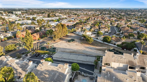 Panoramic view of a residential area with numerous houses, roads, and some trees, seen from above.