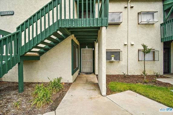 Front view of a multi-story building with green stairs and windows.