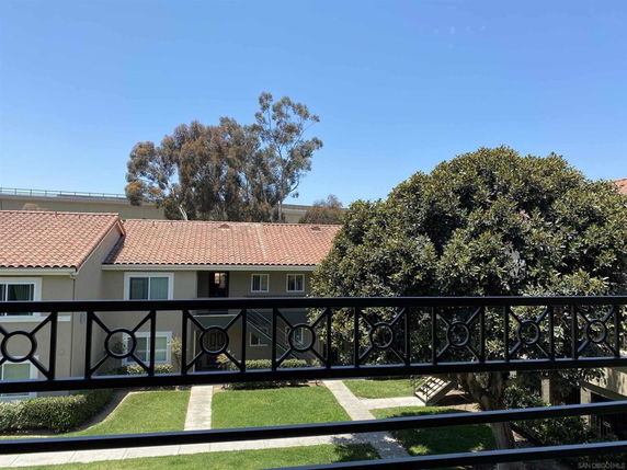 View from a balcony overlooking a courtyard with trees and adjacent buildings.