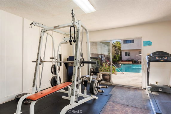 Indoor gym area with exercise equipment and a view of the swimming pool outside.
