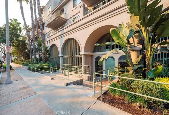 Front view of a multi-story building with arched entryways and balconies.