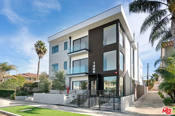 Front view of a modern three-story building with large glass windows and balconies.