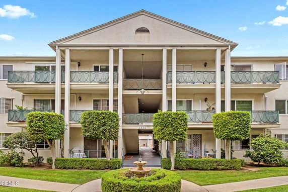 Front view of a three-story apartment building with balconies and columns.