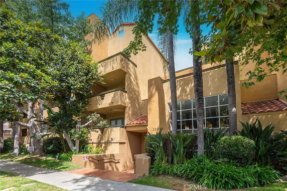 Front view of a multi-story building with balconies and trees.