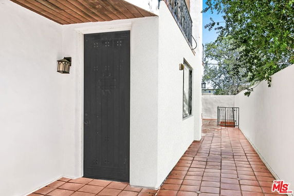 Side view of a house with a black door and a walkway with tiles.