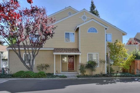 Front view of a two-story house with a red door and multiple windows.