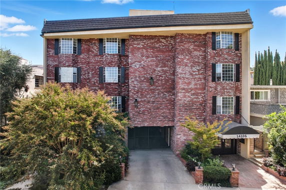 Front view of a multi-story brick building with a central entrance and multiple bay windows.