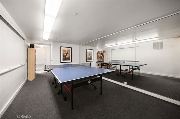 Room with a table tennis setup and wall mirrors.