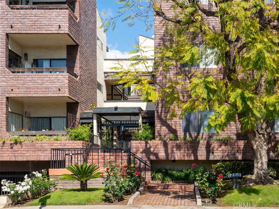 Front view of a multi-story brick apartment building with balconies.