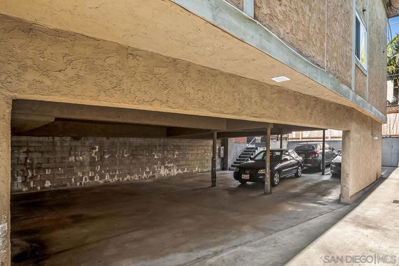 Covered parking area beneath a building with multiple cars parked.