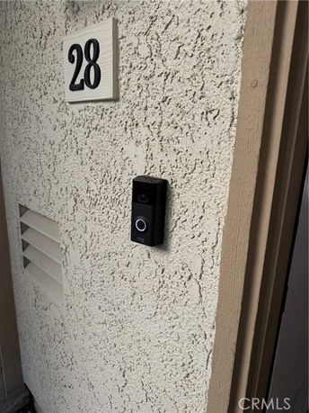 Front exterior of a building wall with doorbell and number 28.