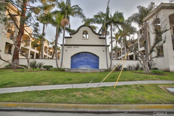 Front view of a multi-story building with an arched entrance and palm trees.