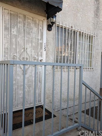 Front view of a building entrance with a metal security door and barred window.