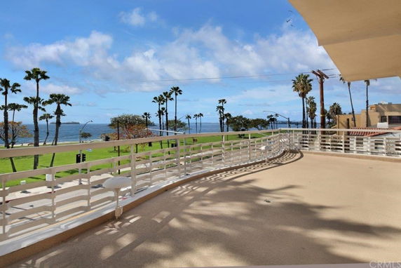 Panoramic view from a terrace overlooking a beach with palm trees and ocean.