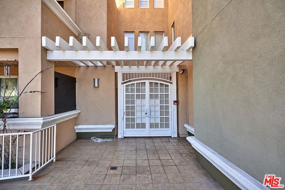 Front view of a building with a white pergola and a gated entrance.