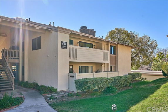 Front view of a two-story residential building with balconies and an external staircase.