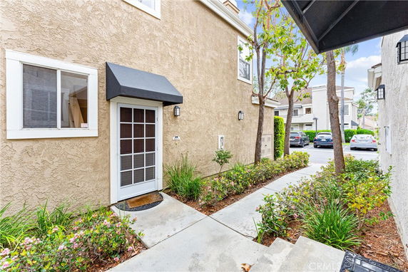 Front door of a house with a small awning and adjacent sidewalk.