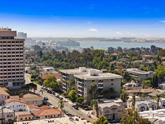 Aerial view of a residential neighborhood with mid-rise buildings and a distant view of water and shoreline.