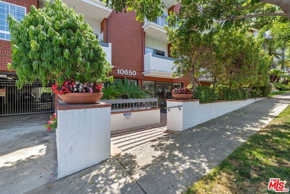 Front view of a residential building with brick facade and potted plants.
