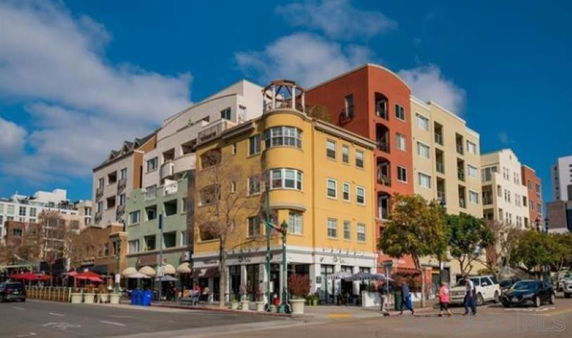 Front view of a multi-story residential building with colorful facades and street-level shops.
