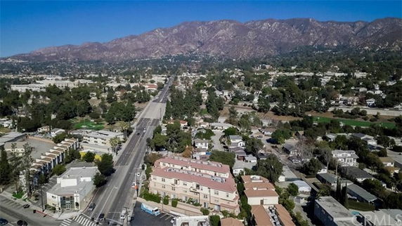 Aerial panoramic view of a landscape with roads, buildings, and mountains in the background.