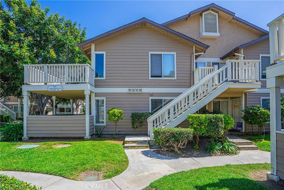 Front view of a two-story residential building with wooden siding and elevated staircases.