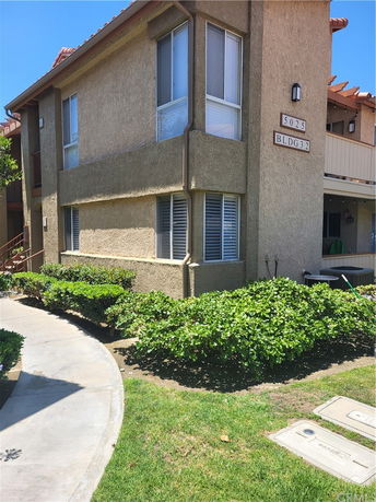 Front view of a two-story residential building with stucco exterior and multiple windows.