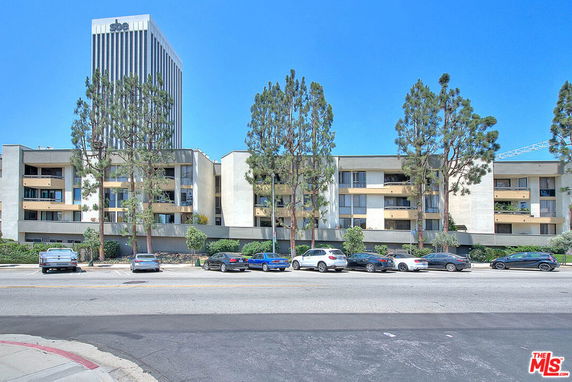 Front view of a multi-story apartment building with balconies and large windows.