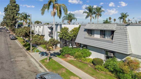 Front view of a residential building with pitched roof and palm trees.