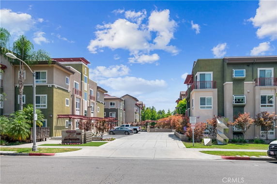 Front view of a multi-story apartment building with balconies and surrounding landscaping.