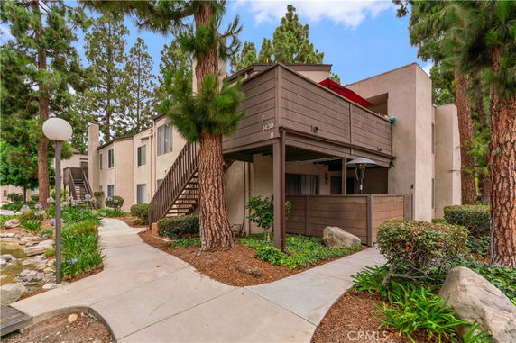 Front view of a multi-level apartment building with exterior stairs in a landscaped area.