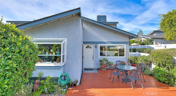 Front view of a single-story house with a deck and outdoor seating area.