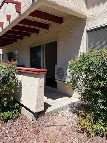 Front view of a building with a balcony and air conditioning unit.