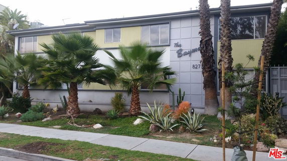 Front view of a multi-story building with palm trees in front.